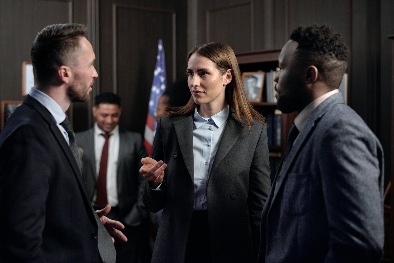 Trois personnes discutant debout dans un bureau américain