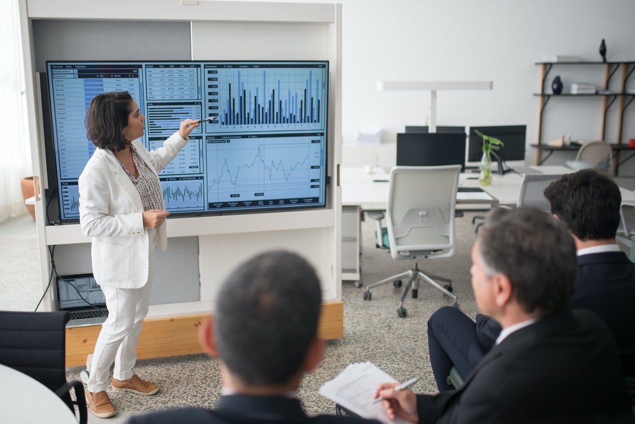 Femme qui montre des données financières à un groupe d'analystes financiers