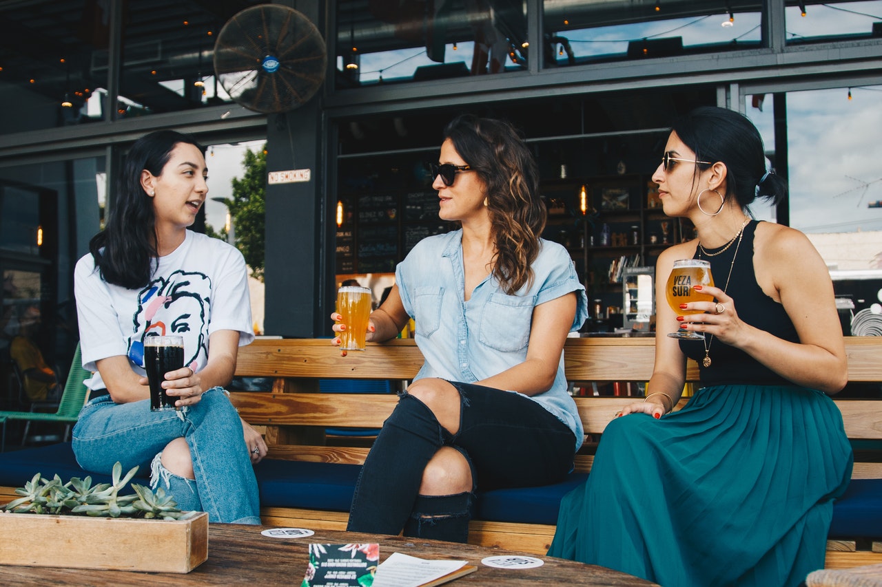 Trois femmes discutant sur un banc avec un verre d'alcool à la main